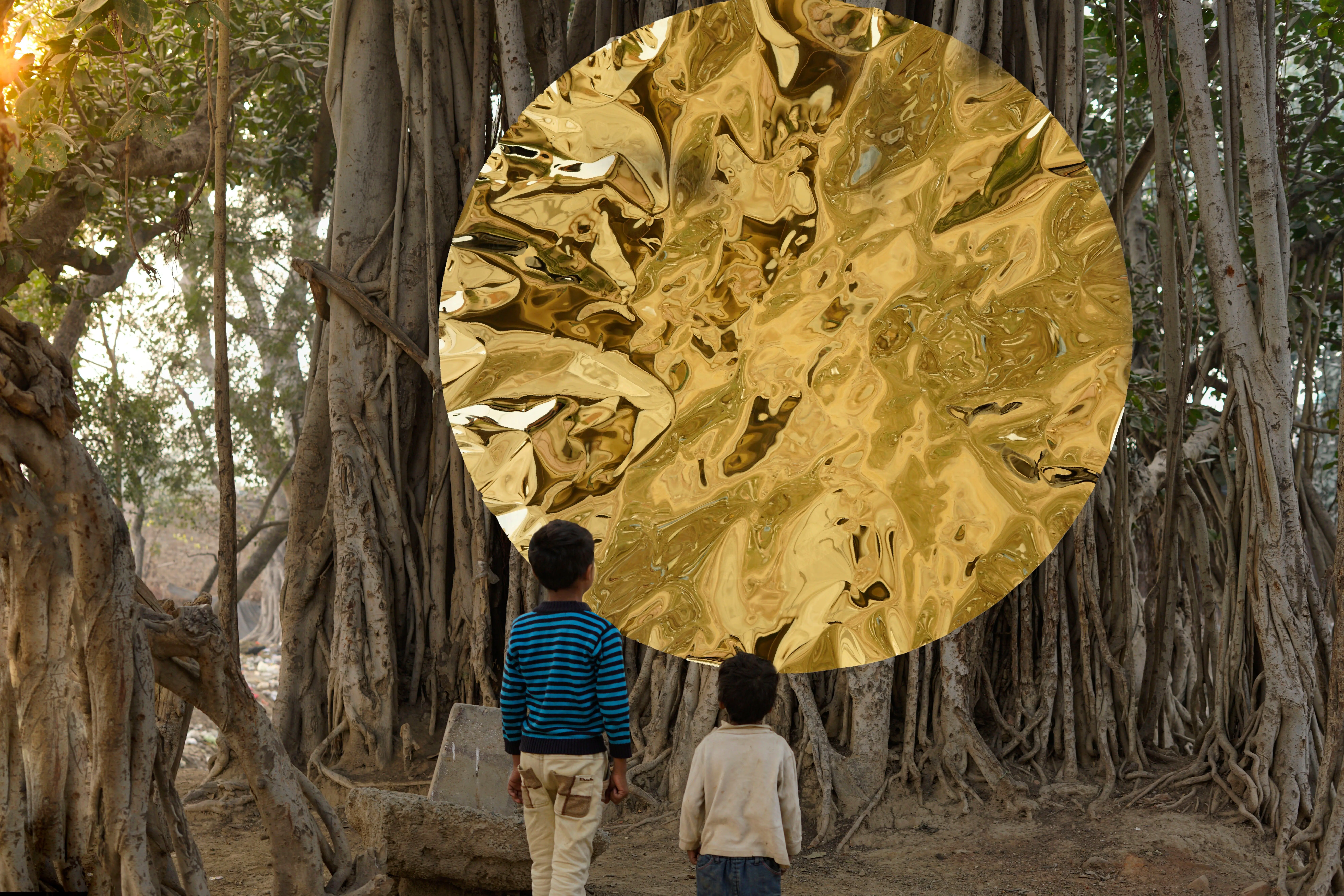 Gold mirror disc suspended among banyan roots, with children