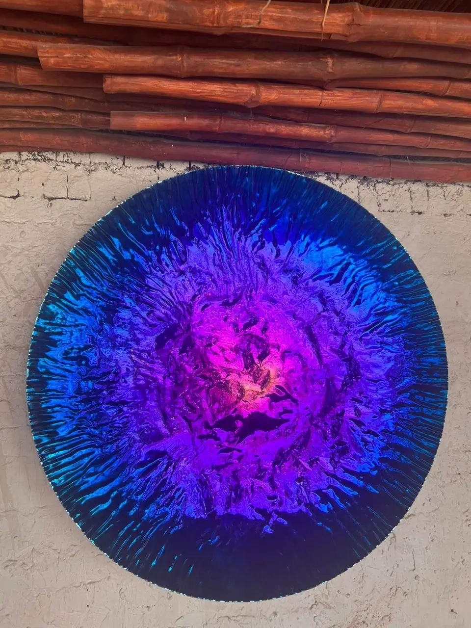 Iridescent indigo mirror disc with a radial burst pattern